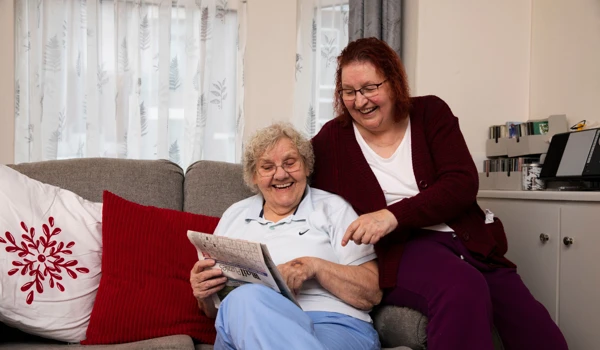 Older Woman And Woman Looking At Newspaper Together On Newspaper