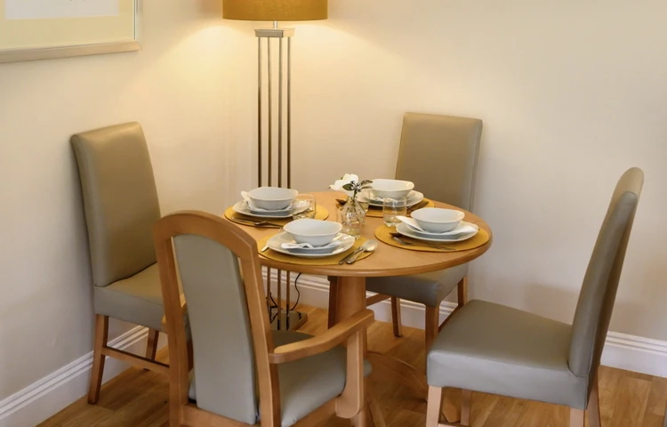 Dining table set for dinner with a tall lamp lit in the background