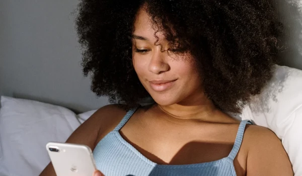 Woman Sitting In Bed With Phone