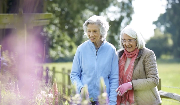 Two Older Women Admiring The Plants In The Garden
