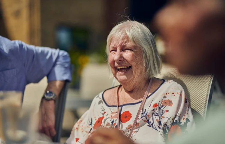 Older Woman Enjoying The Sunshine With Other Residents