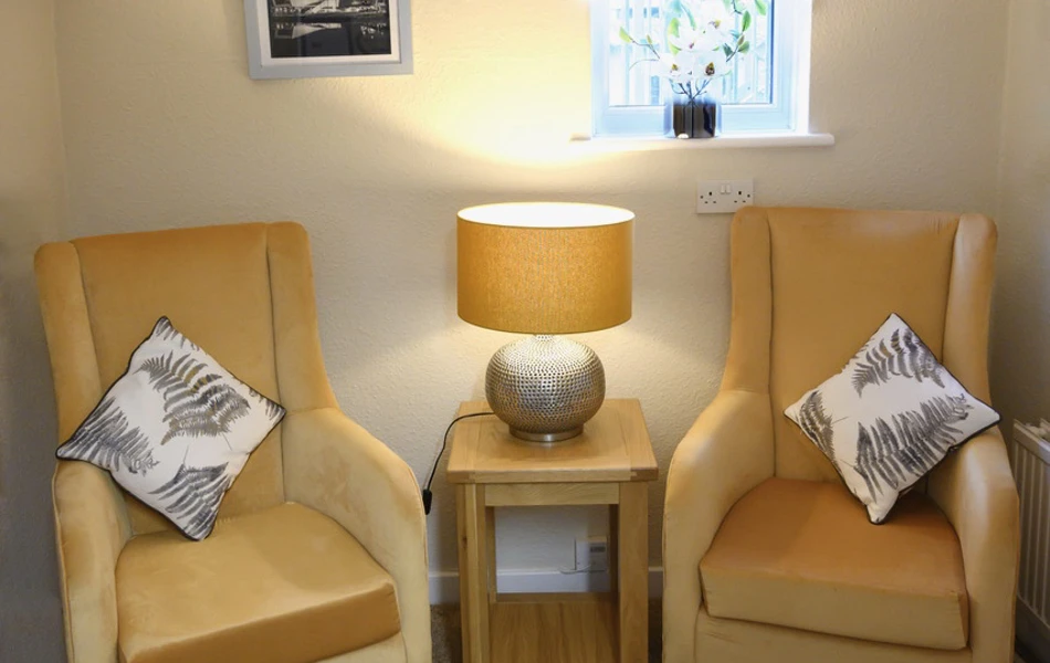 Snug area with two yellow chairs and a lit table lamp