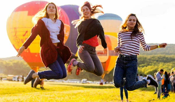 Group Of Women Jumping In Front Of Hot Air Ballooons
