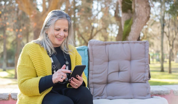 Older Woman Looking At Her Phone In The Garden